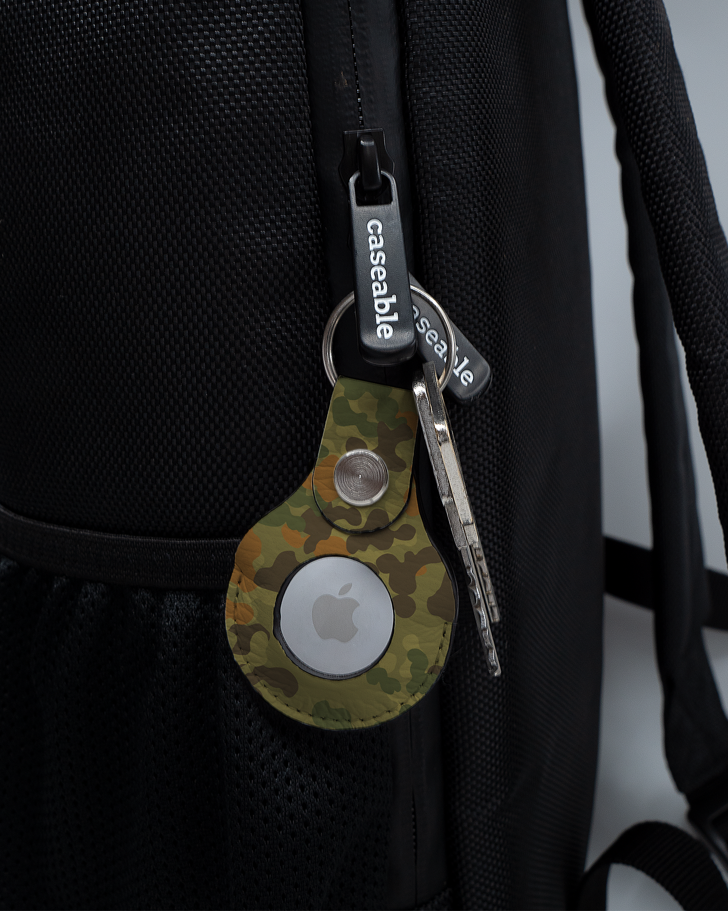 AirTag Holder with design Spot Camo attached to a bag