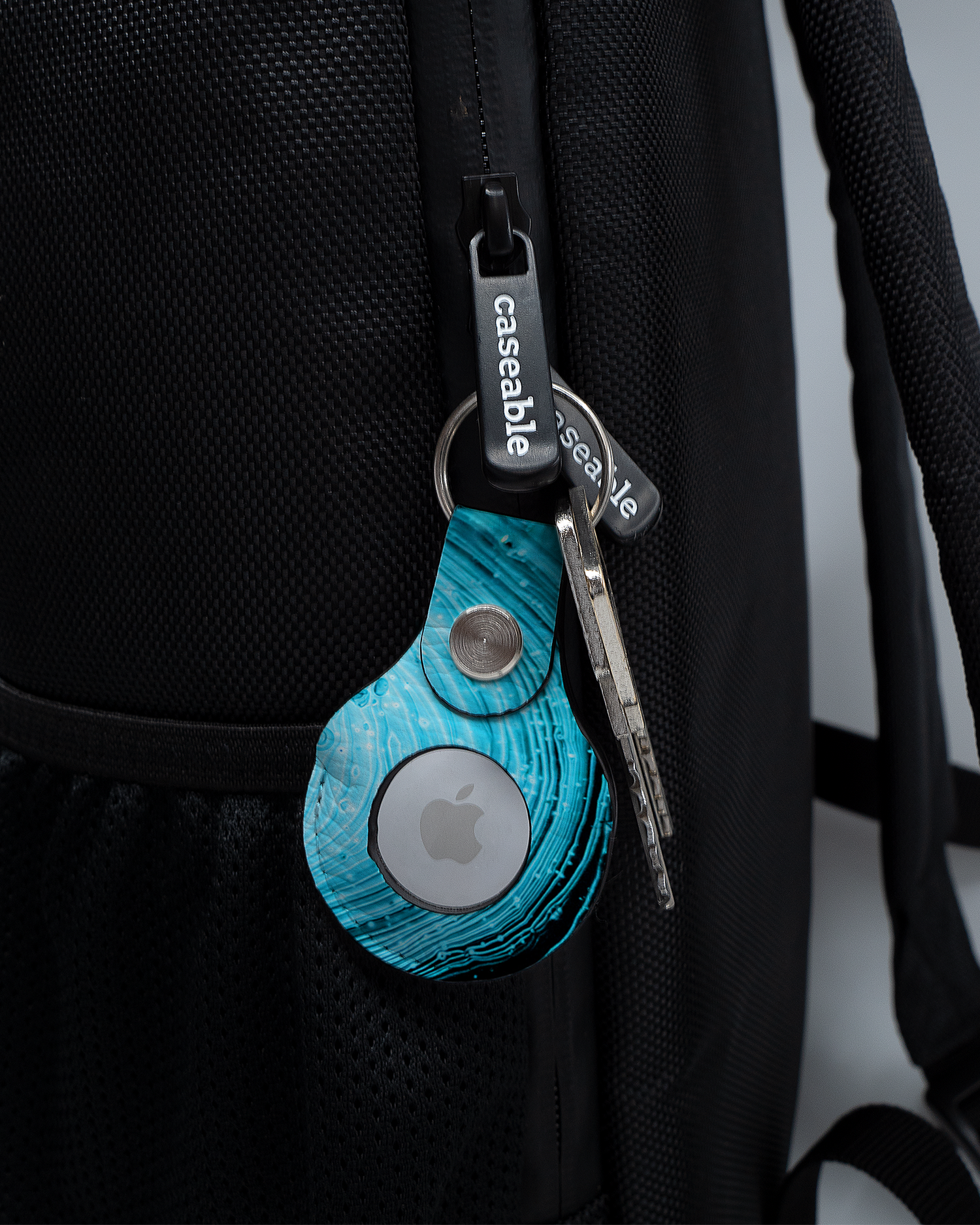 AirTag Holder with design Turquoise Ripples attached to a bag