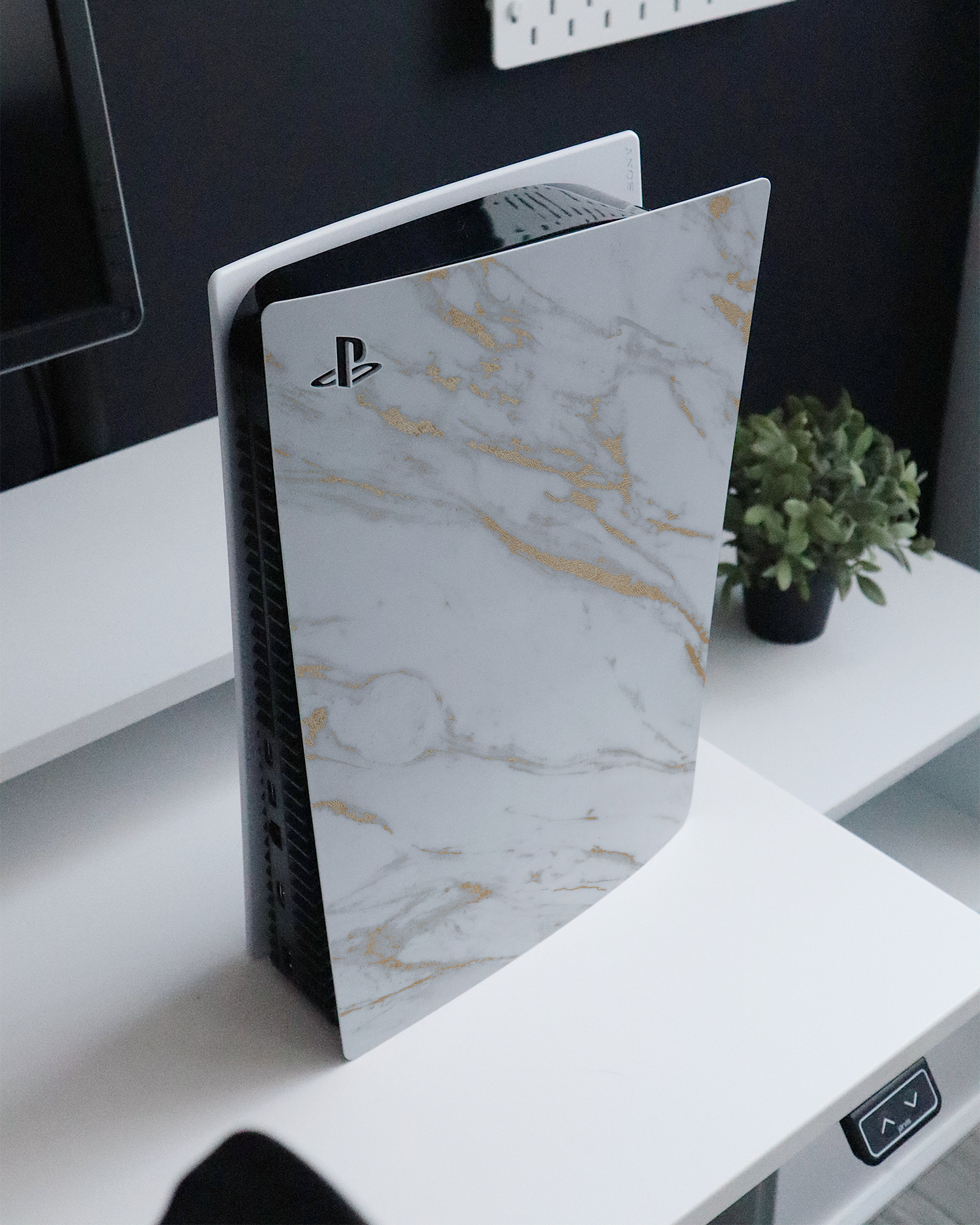 Gold Marble Elegance Console Skin for Sony PlayStation 5 standing on a sideboard 