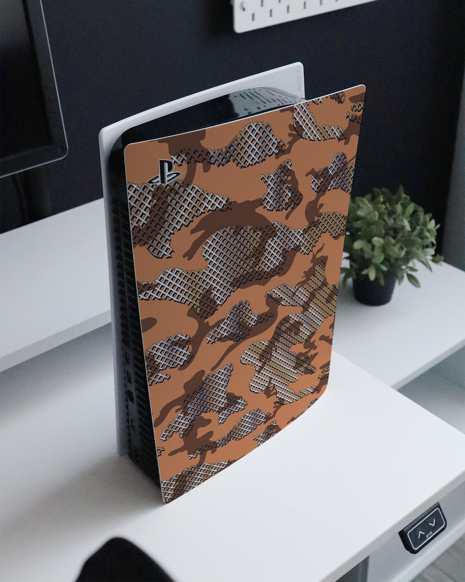 Fall Camo IV Console Skin for Sony PlayStation 5 standing on a sideboard 