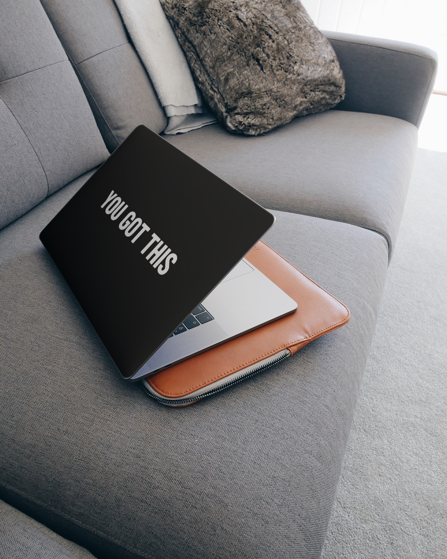 You Got This Black Laptop Skin for 15 inch Apple MacBooks on a couch